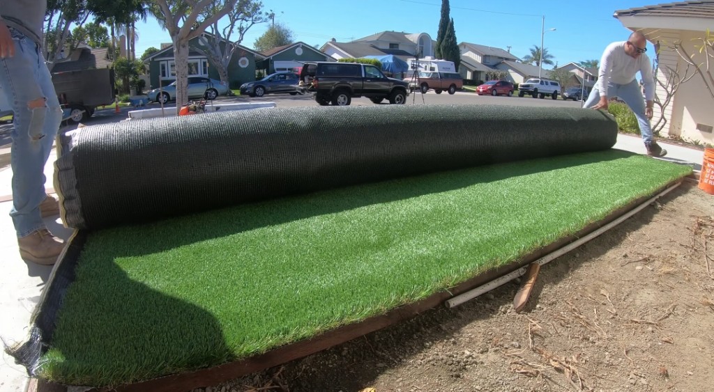 Professional artificial grass installation team rolling out turf in Georgetown, TX